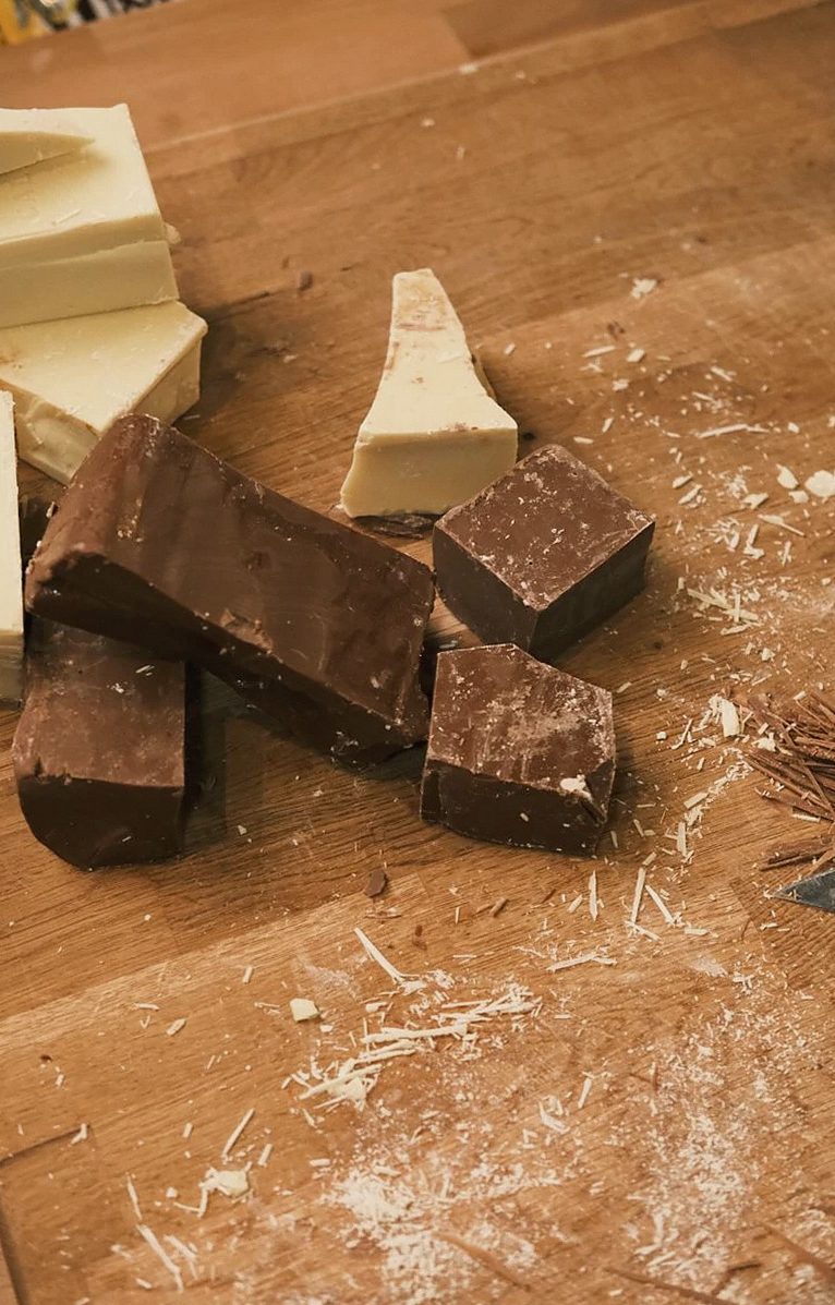 素朴な木の表面に置かれたダークチョコレートとホワイトチョコレートの塊、グルメ料理に最適。